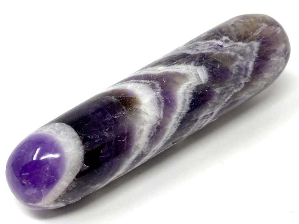 Crystal wand made of polished Chevron Amethyst crystals, showing a crystal massage wand shape with two rounded ends. Dream Amethyst Crystal Massage Wand with a deep violet purple base colour and a chevron patterned surface with White Quartz chevron shapes